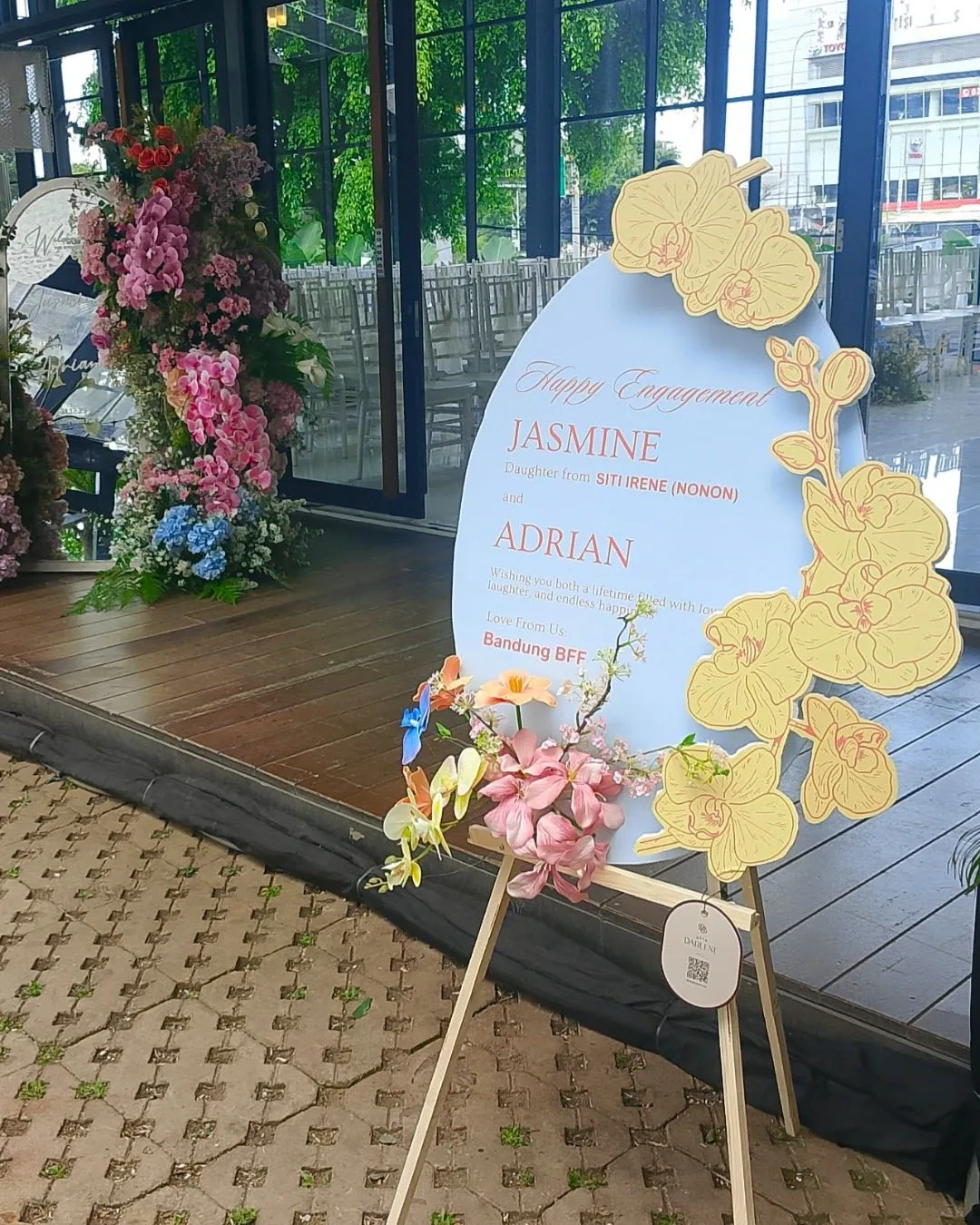 Papan bunga Dear Darlene berdiri di area resepsi pernikahan